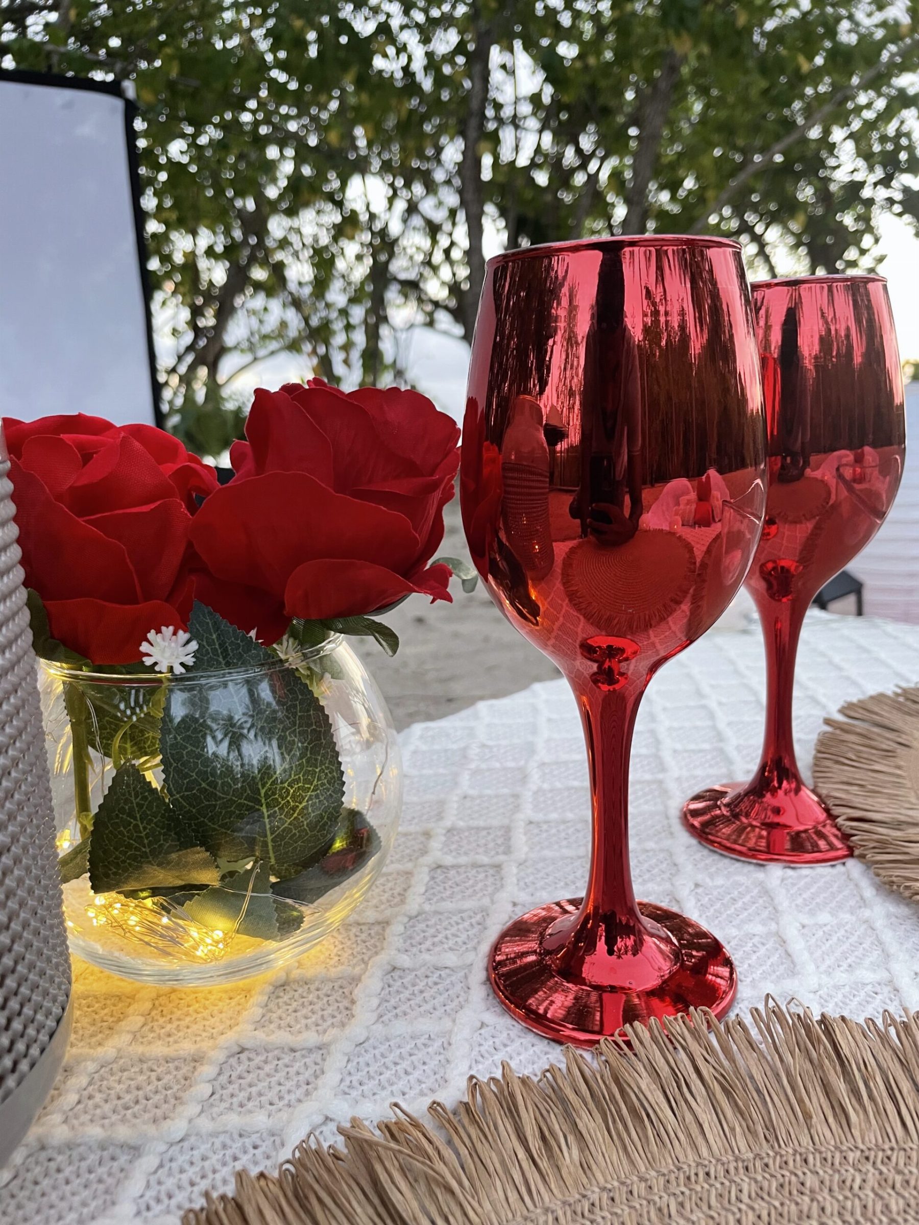 Roses rouges et verres à pied sur la table dressée, face à l'écran