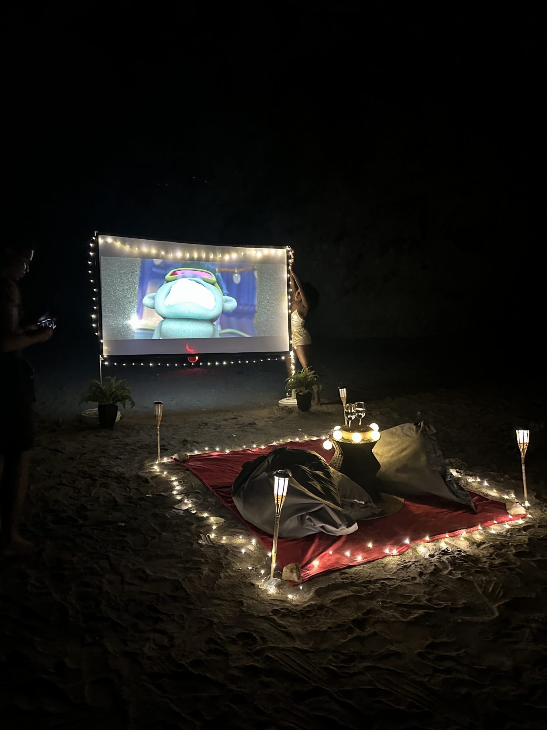 Séance sur la plage à la nuit tombée, écran éclairé de guirlandes